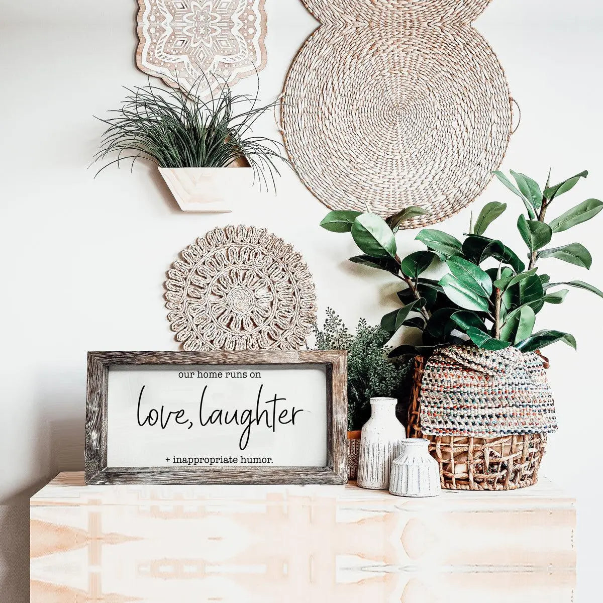 Decorative setup with plants, wicker baskets, and a framed quote on a wooden surface.