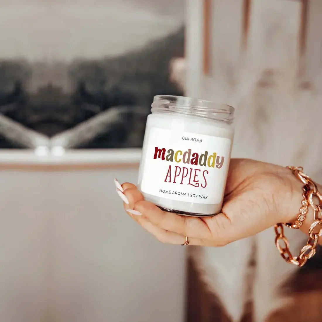 Hand holding a 'comfy & cozy' candle with a blurred background