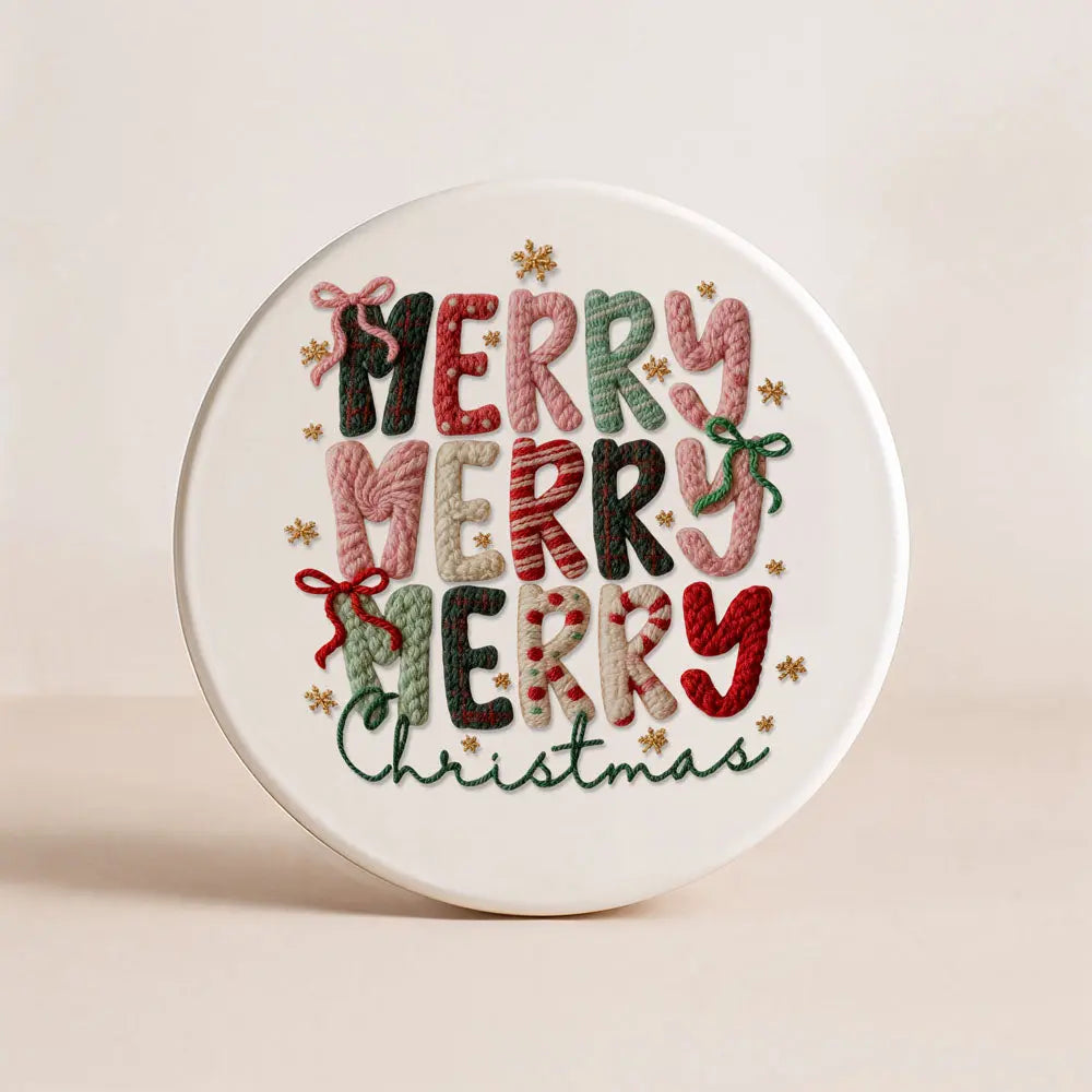 Round white coaster with embroidered 'Merry Christmas' text on a beige background