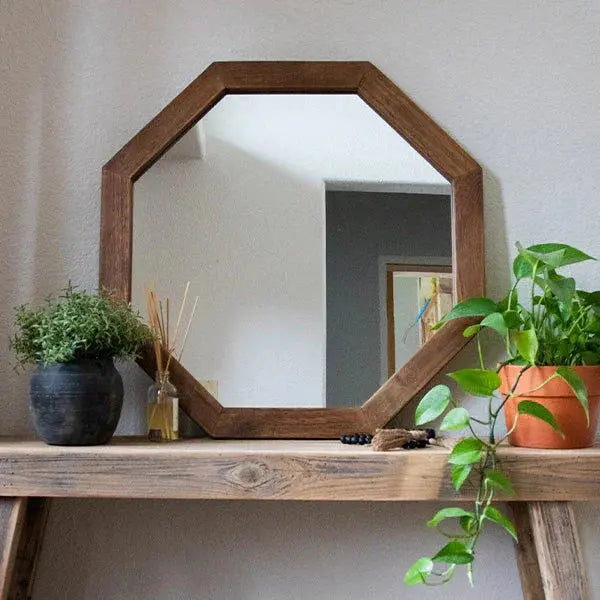 Octagon wood-framed mirror on rustic shelf with potted plants, farmhouse decor