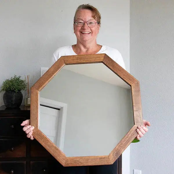 Woman holding large octagon wood-framed mirror for farmhouse or cottage style home decor