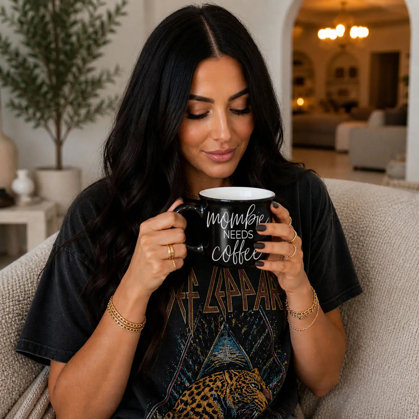 Woman holding a black mug with 'Spooky Season' text in a cozy living room.