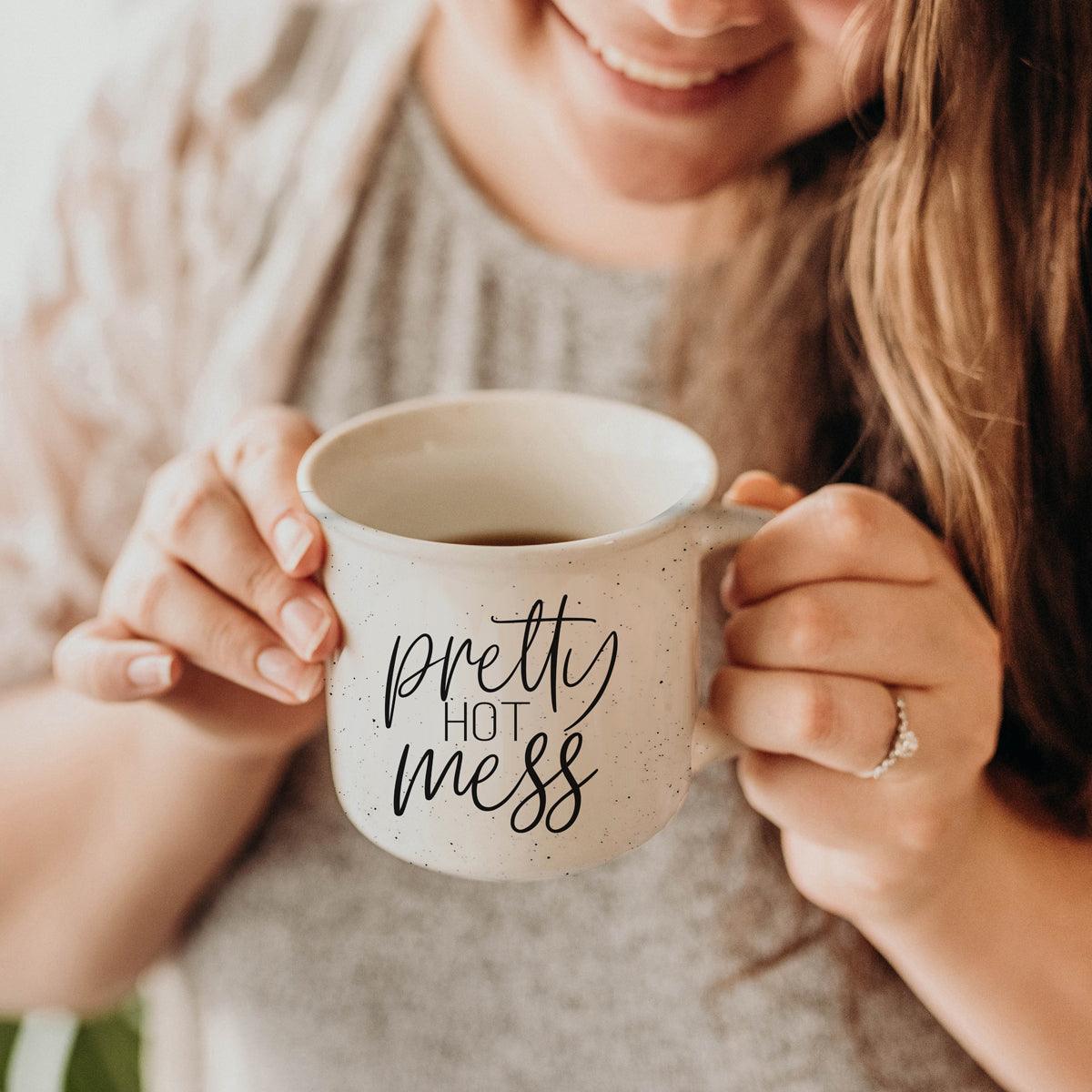 Person holding a mug with 'pretty hot mess' text