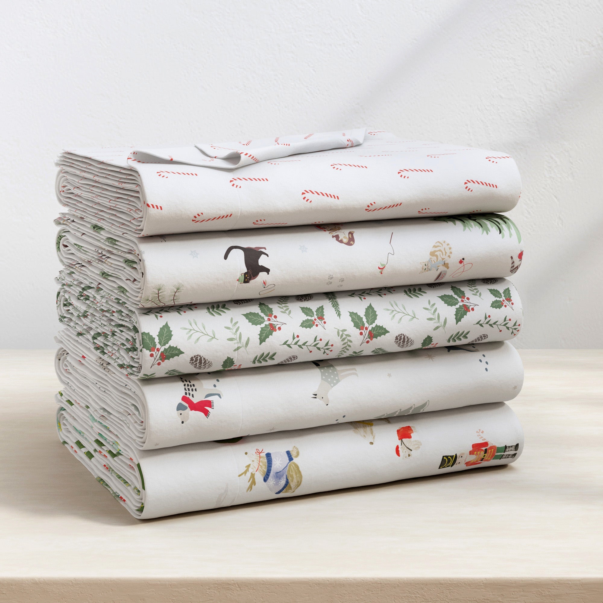 Stack of folded fabric sheets with various patterns on a light surface.