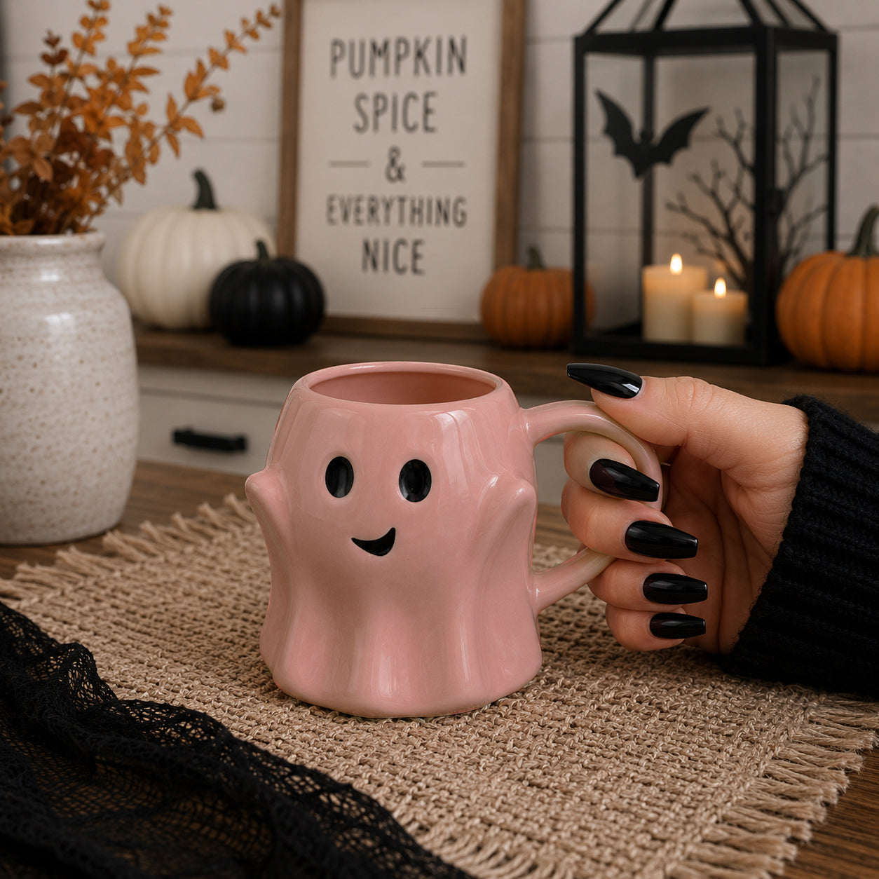 Pink ghost mug with a hand holding it, set against a Halloween-themed background with pumpkins and candles.