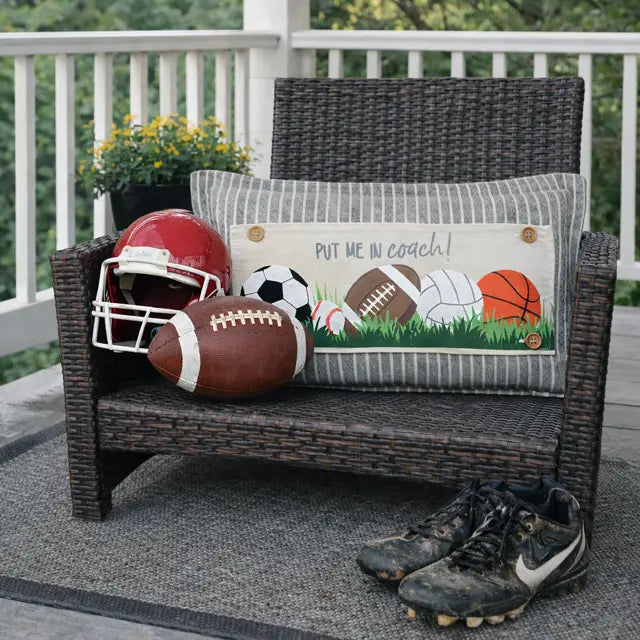 Wicker chair with sports-themed pillow and balls on a deck