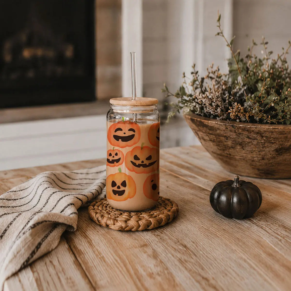 Glass mug with coffee and 'hocus pocus, I need coffee to focus' text on a wooden surface with a pumpkin and plant.