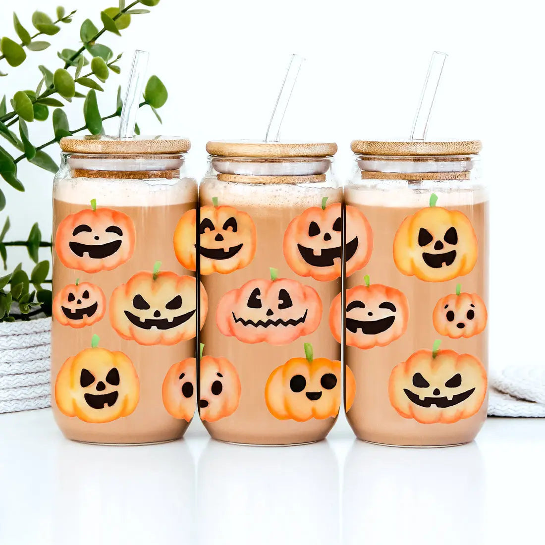 Three glass jars with pumpkin face designs on a white background