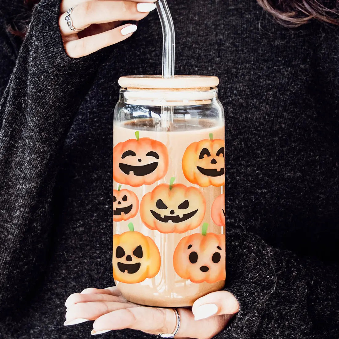 Glass jar with pumpkin design held by a person wearing a dark sweater.