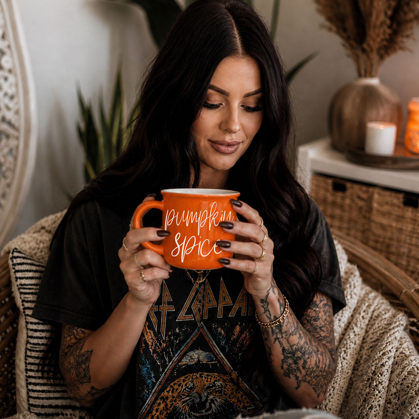 Woman holding an orange mug with text, sitting in a cozy indoor setting.