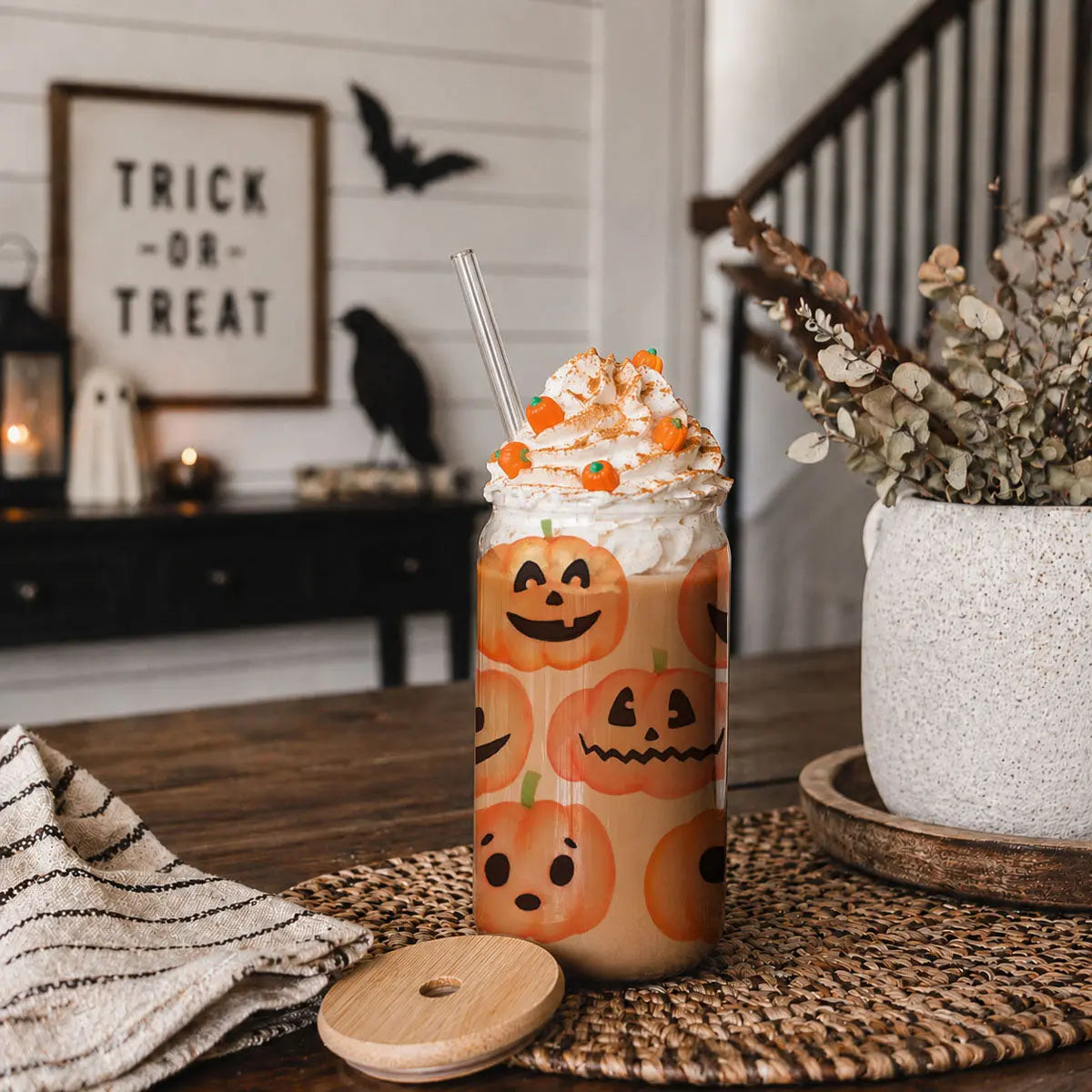 Halloween-themed drink with pumpkin design on a table with decorative elements.