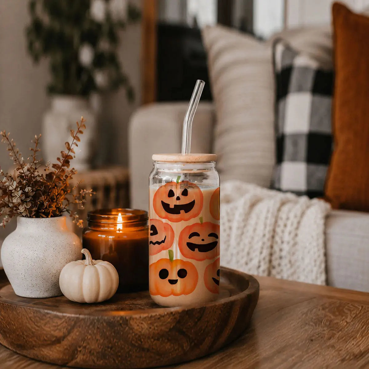 Glass tumbler with Halloween design on a wooden tray in a cozy living room.