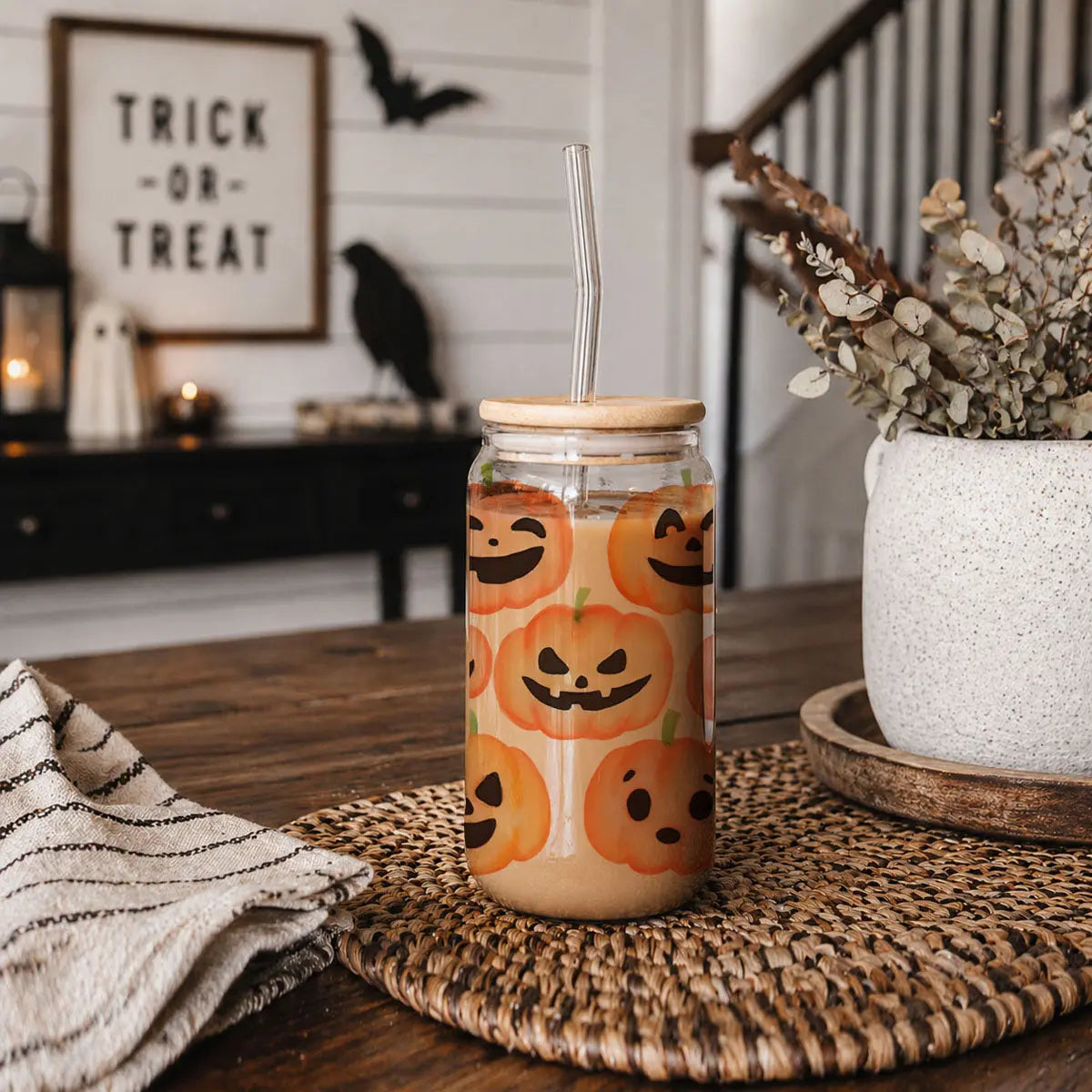 Jar with pumpkin design on a table with Halloween decorations in the background