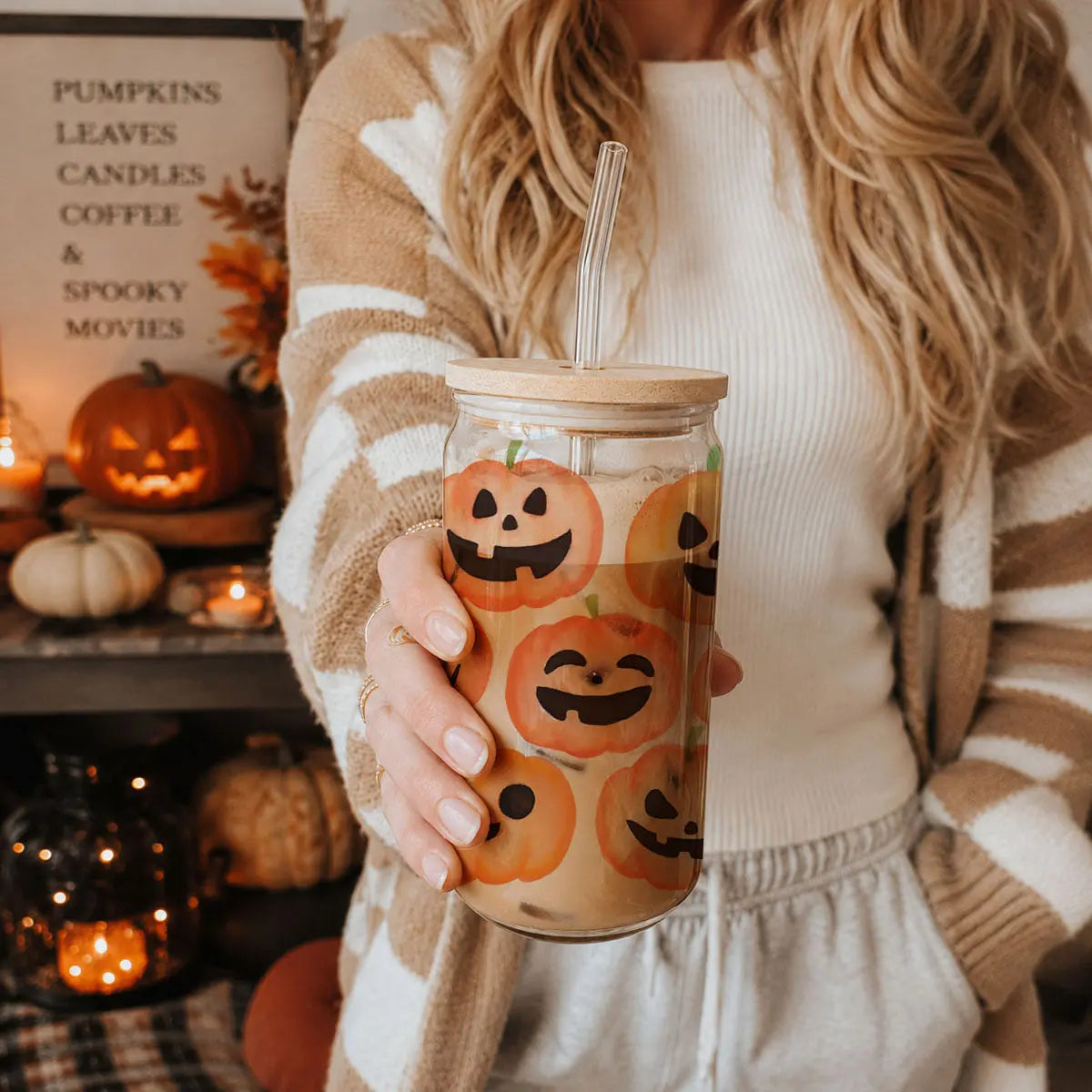 Person holding a tumbler with Halloween-themed design in a cozy indoor setting.