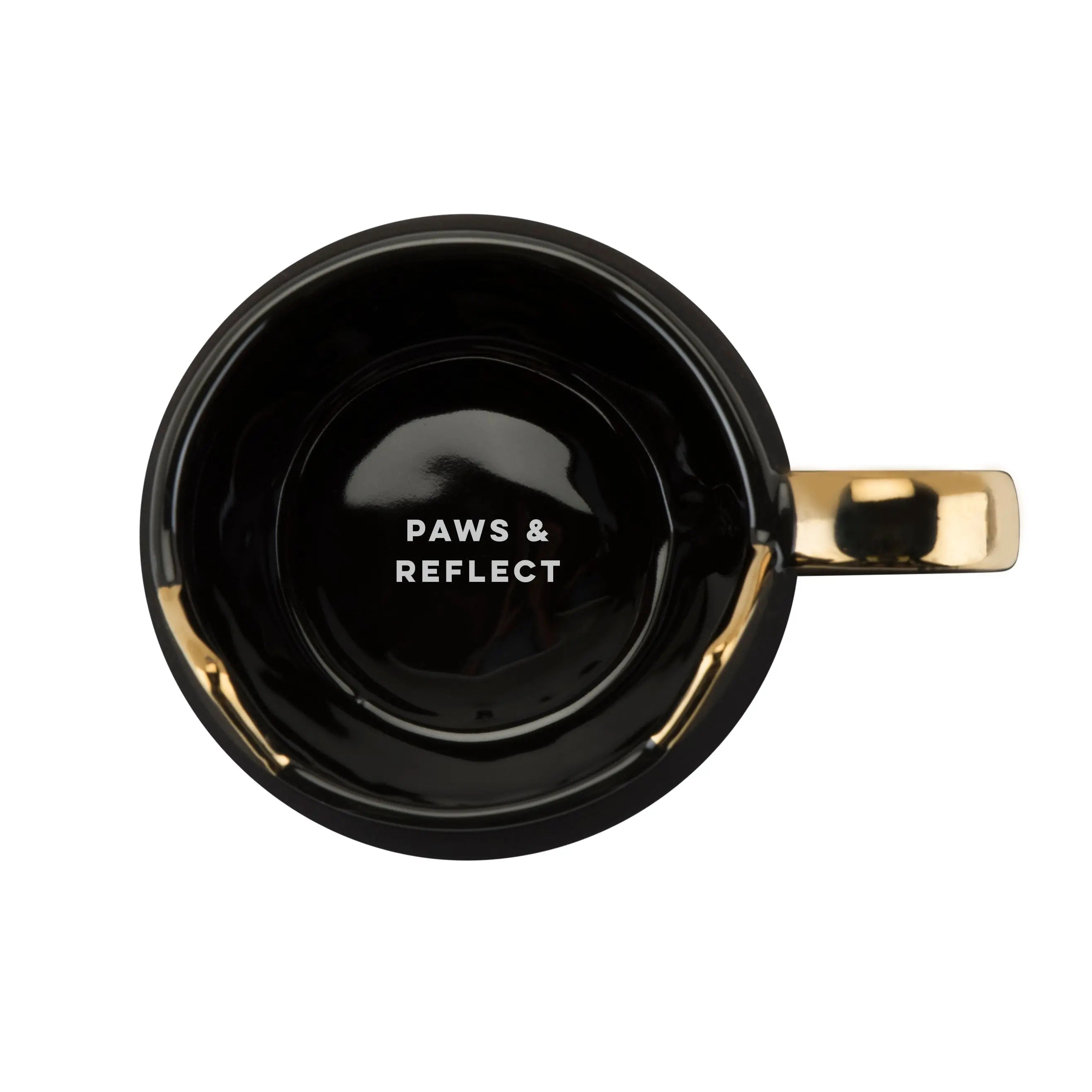 Black mug with gold handle featuring 'PAWS & REFLECT' text on a white background
