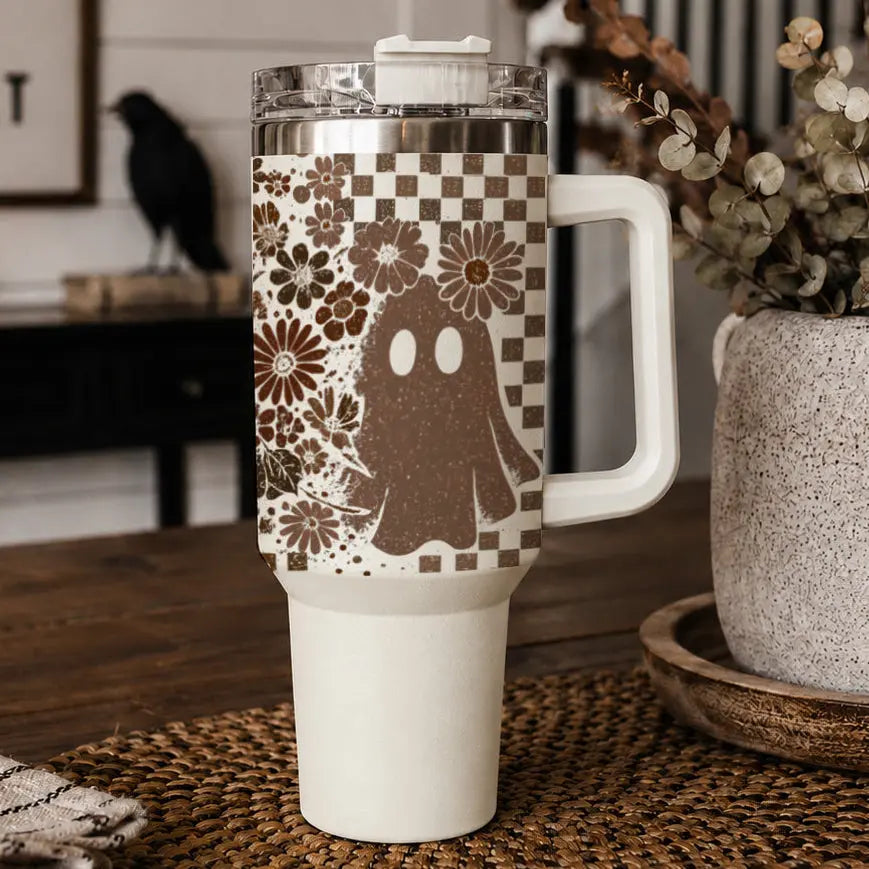 White tumbler with floral and ghost design on a wooden surface