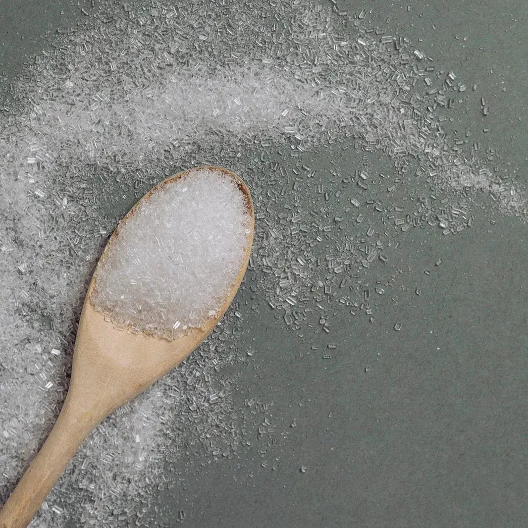 Wooden spoon with coarse bath salts on gray surface, cozy home spa essentials