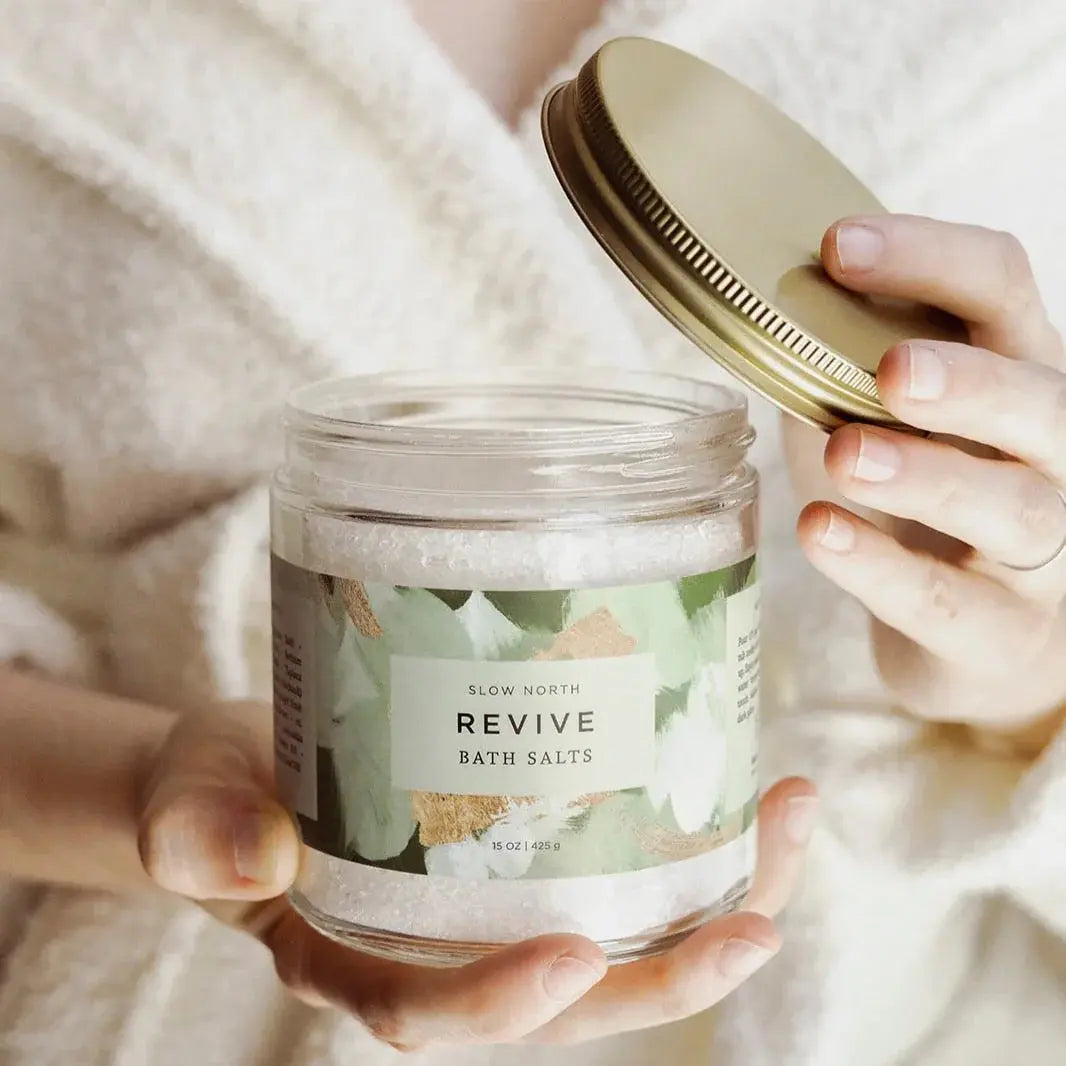 Revive bath salts in glass jar with gold lid, held by person in cozy robe, farmhouse spa essentials