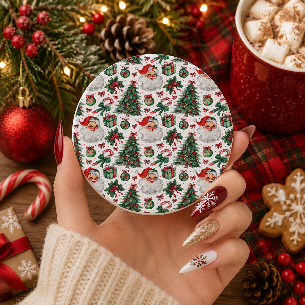 Hand holding a Christmas-themed coaster with festive design, surrounded by holiday decorations.