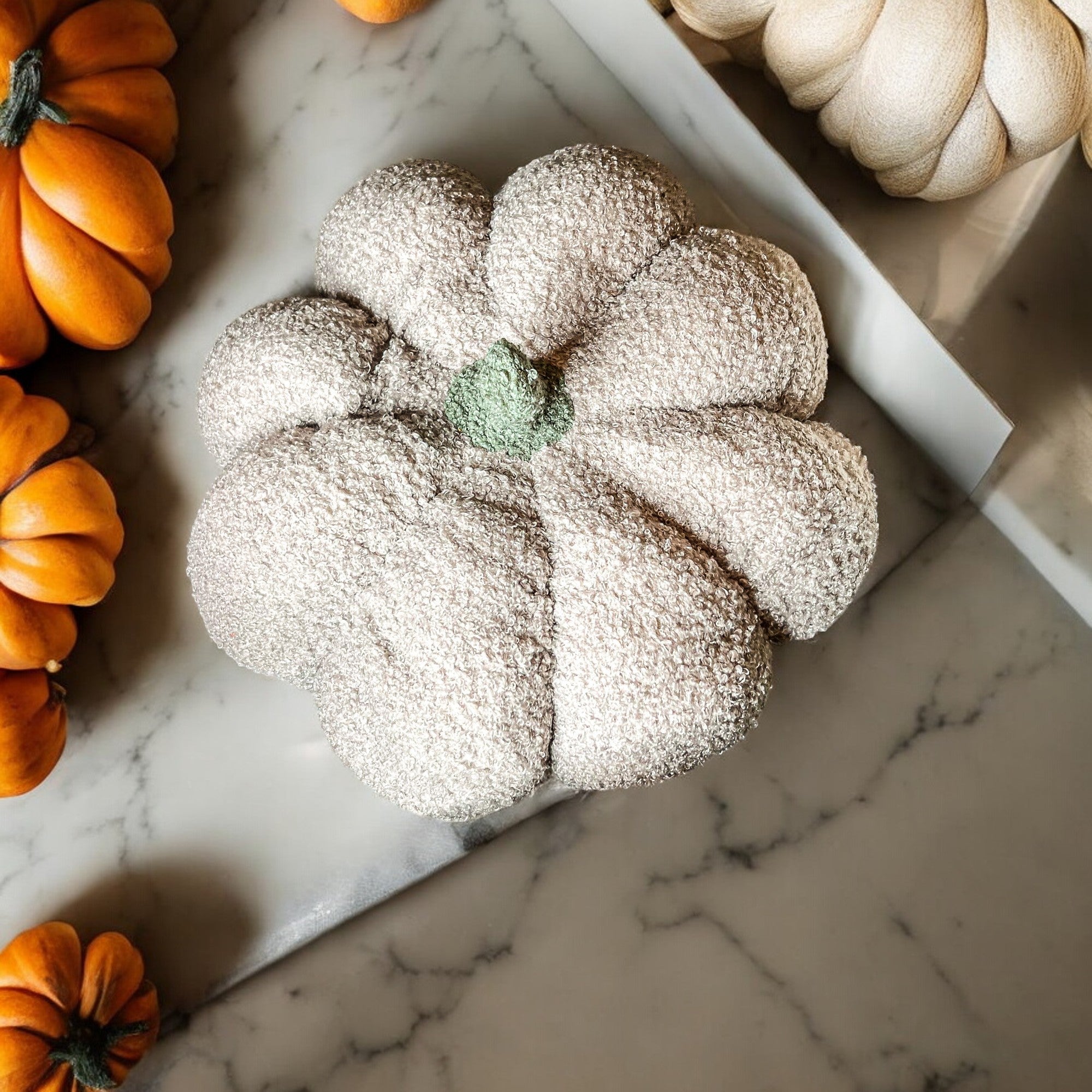 Decorative pumpkin with powdered sugar on a marble surface with other pumpkins.