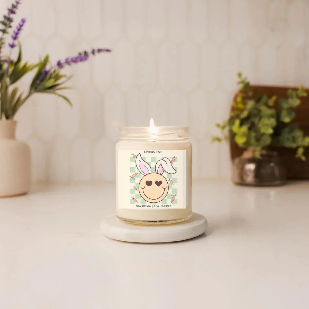 Candle with a bunny design label on a white surface with plants in the background