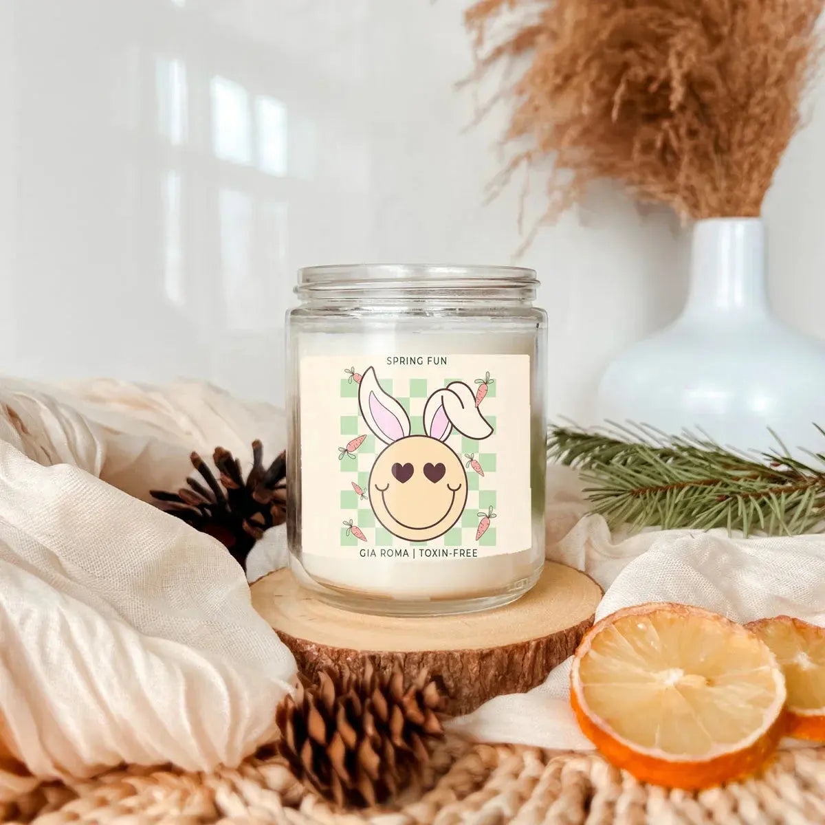 Candle with a bunny design label on a wooden coaster with decorative elements.