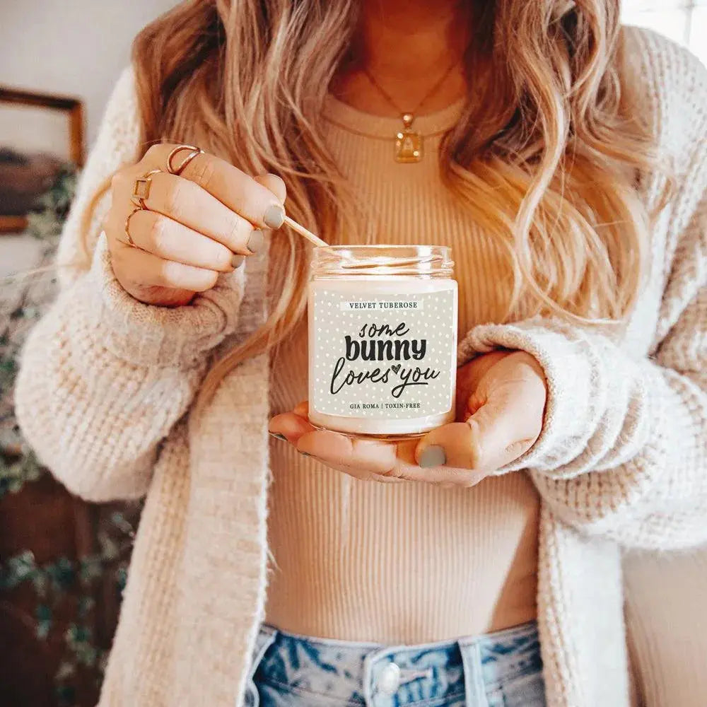Person holding a candle labeled 'some bunny loves you' with a soft focus background