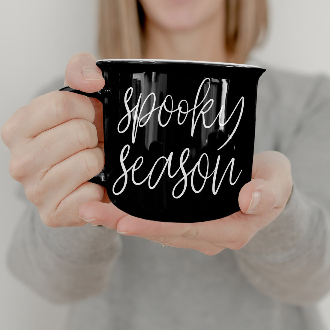 Black mug with 'Spooktacular Season' text held by a person