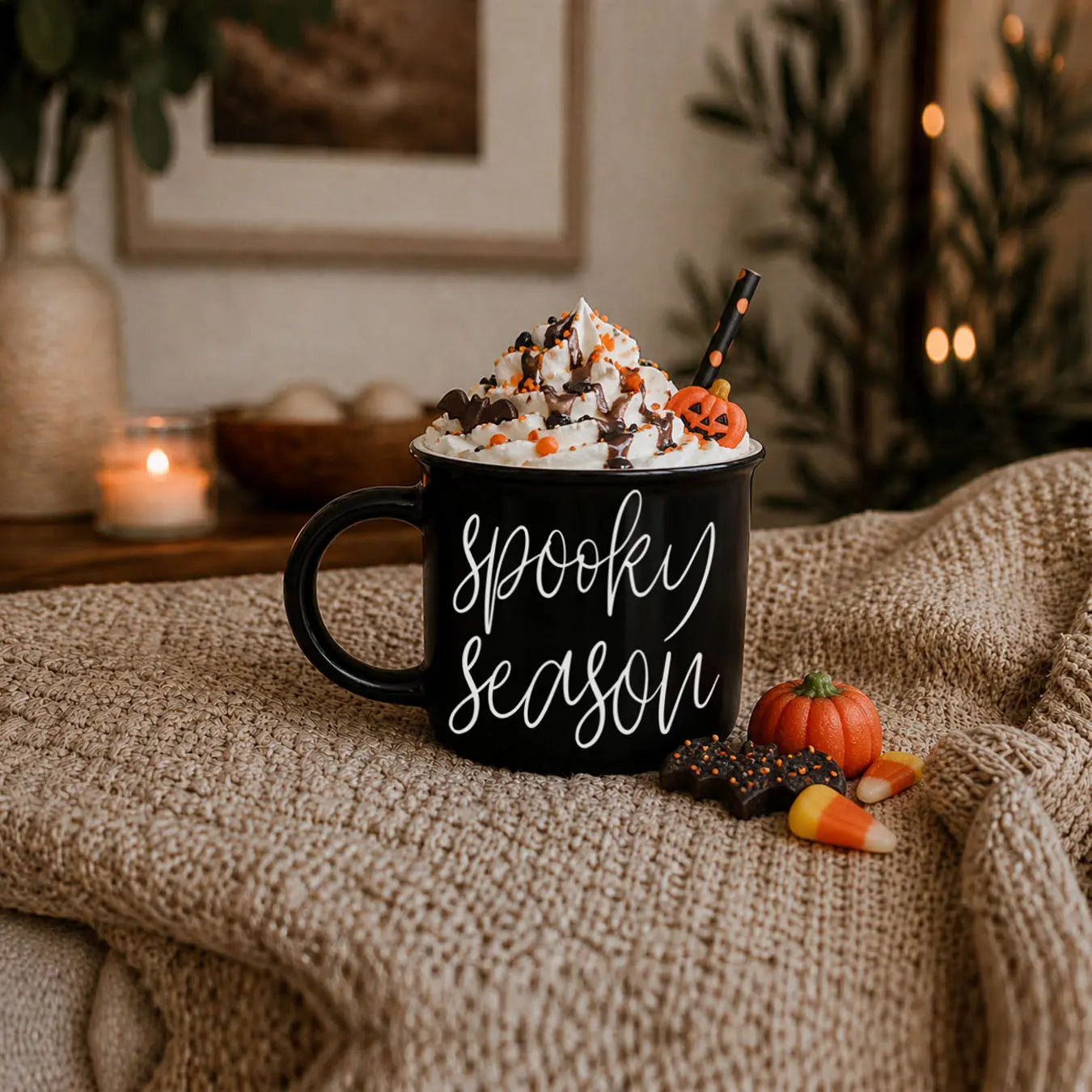 Black mug with 'Spooky Season' text, Halloween-themed toppings, and candy on a textured surface.