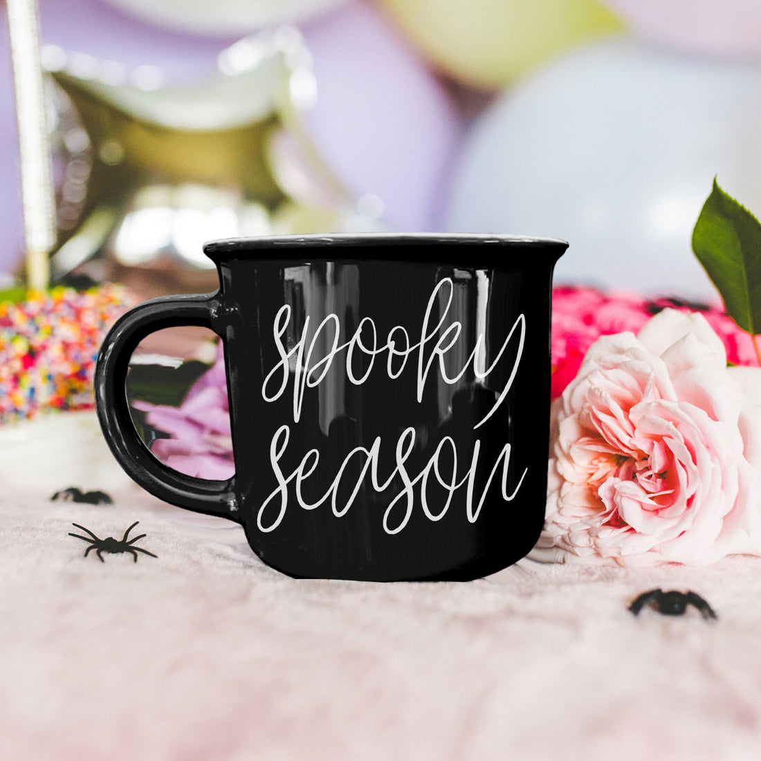 Black mug with 'Spooky Season' text on a decorative background with flowers and Halloween elements.