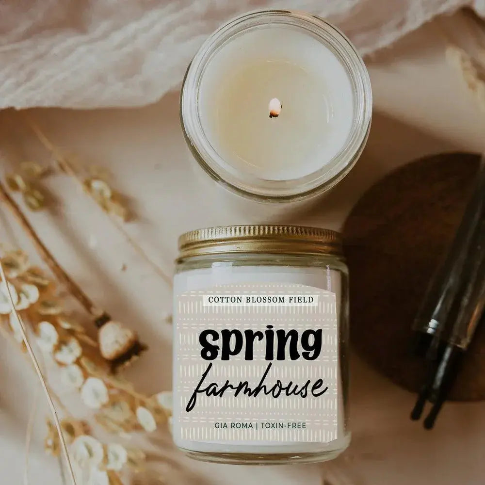 Candle in a jar labeled 'Spring Farmhouse' with decorative elements on a soft background