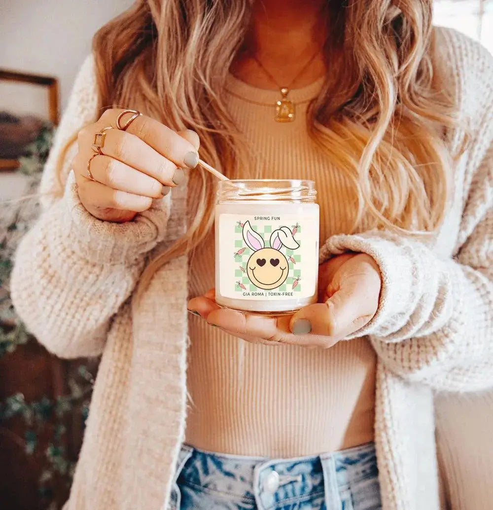 Person holding a 'Cosy Season' candle with a blurred background