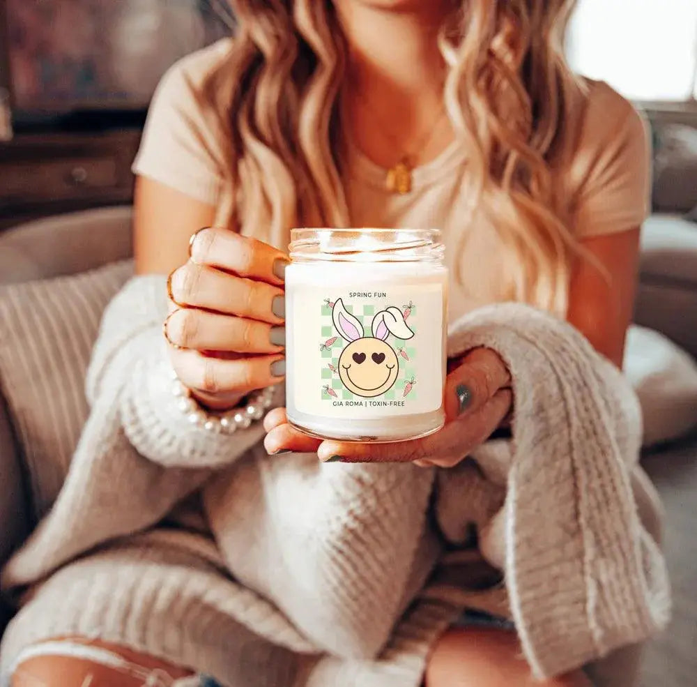 Person holding a candle labeled 'easter vibes' in a cozy indoor setting