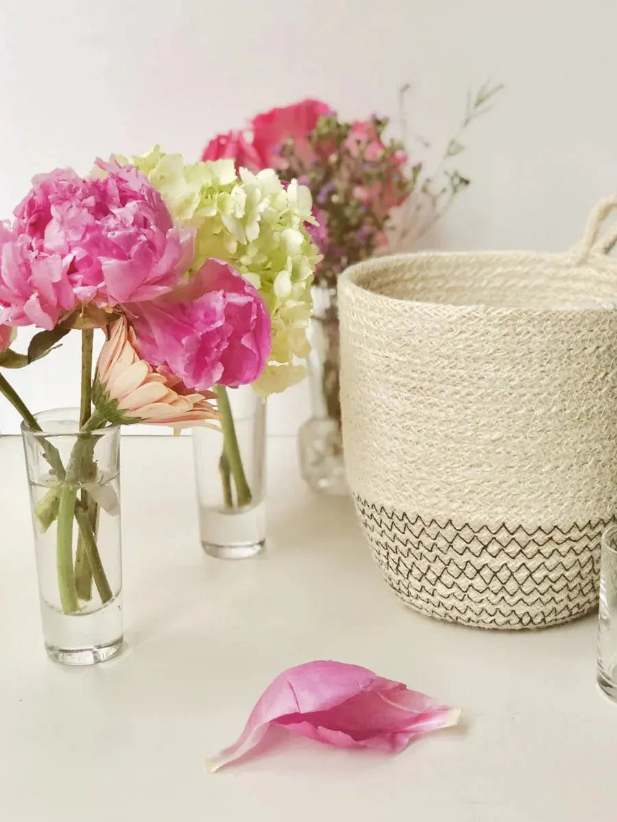 Cozy farmhouse decor with pink peonies, hydrangeas in glass vases, and a woven basket with zigzag trim