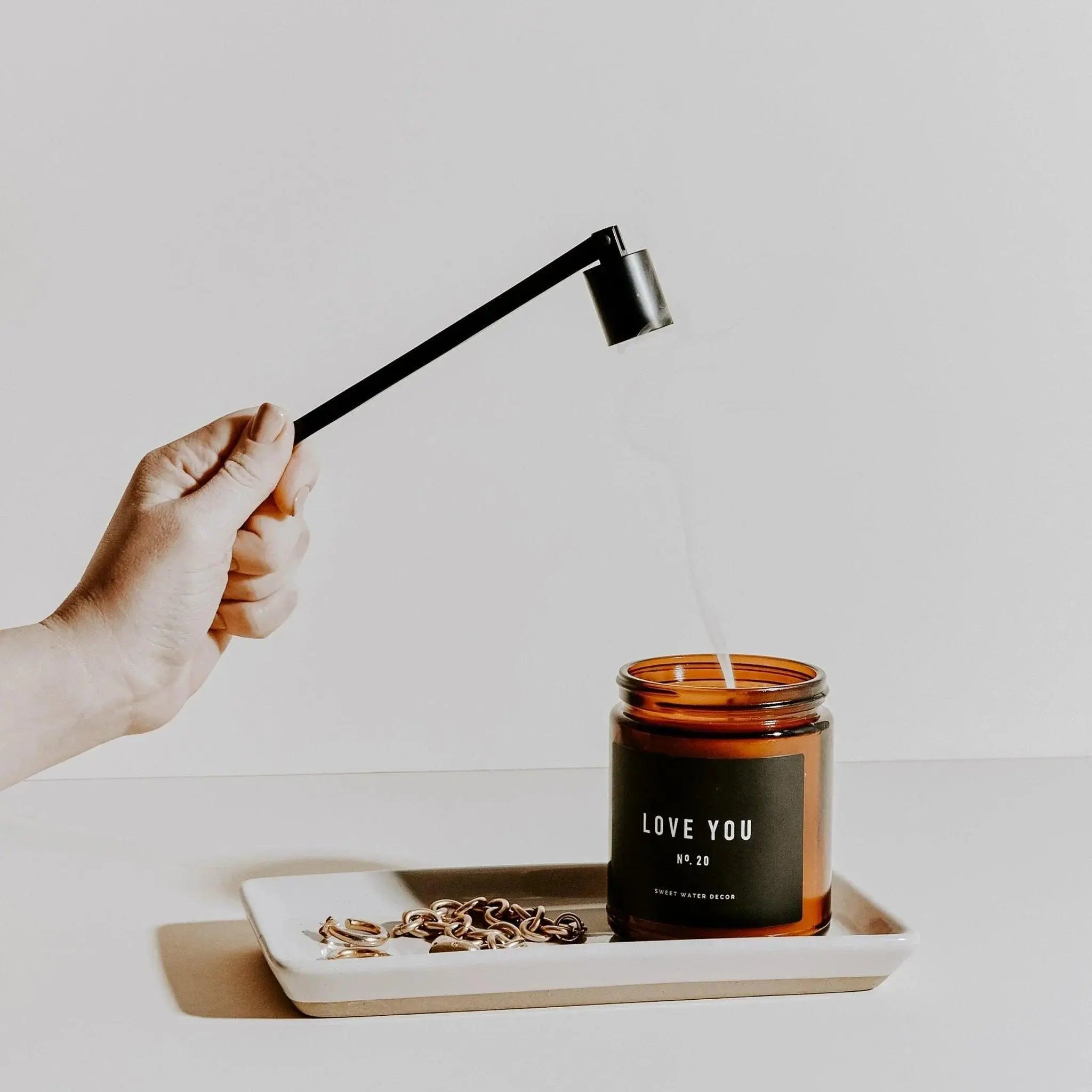 Hand extinguishing 'Love You No. 20' candle with snuffer, cozy home decor vibe