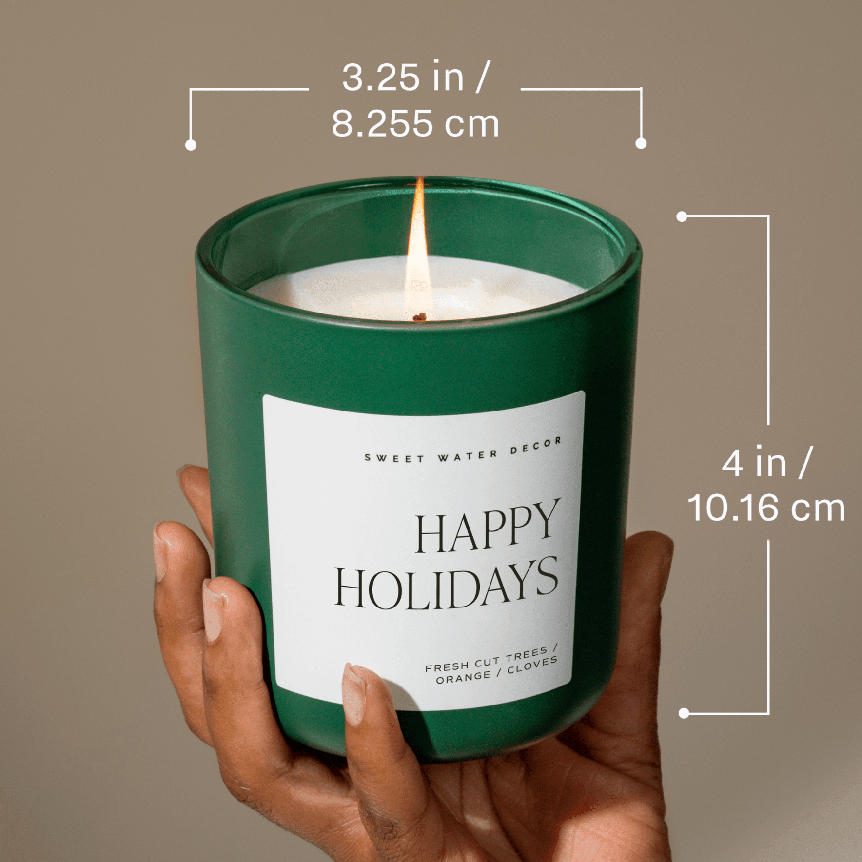 Hand holding a 'Happy Holidays' candle with dimensions displayed
