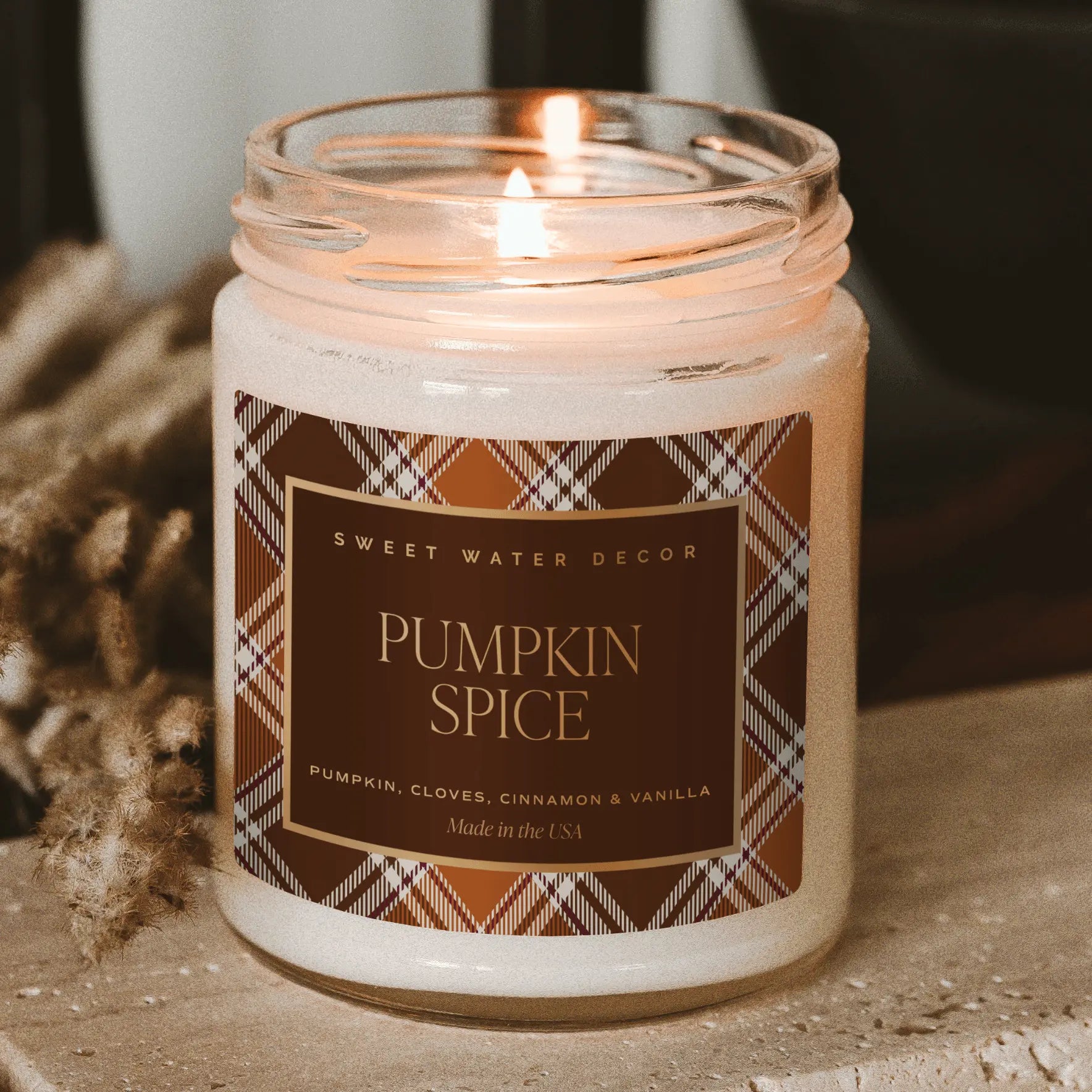 Candle labeled 'Pumpkin Spice' with a plaid design on a neutral background