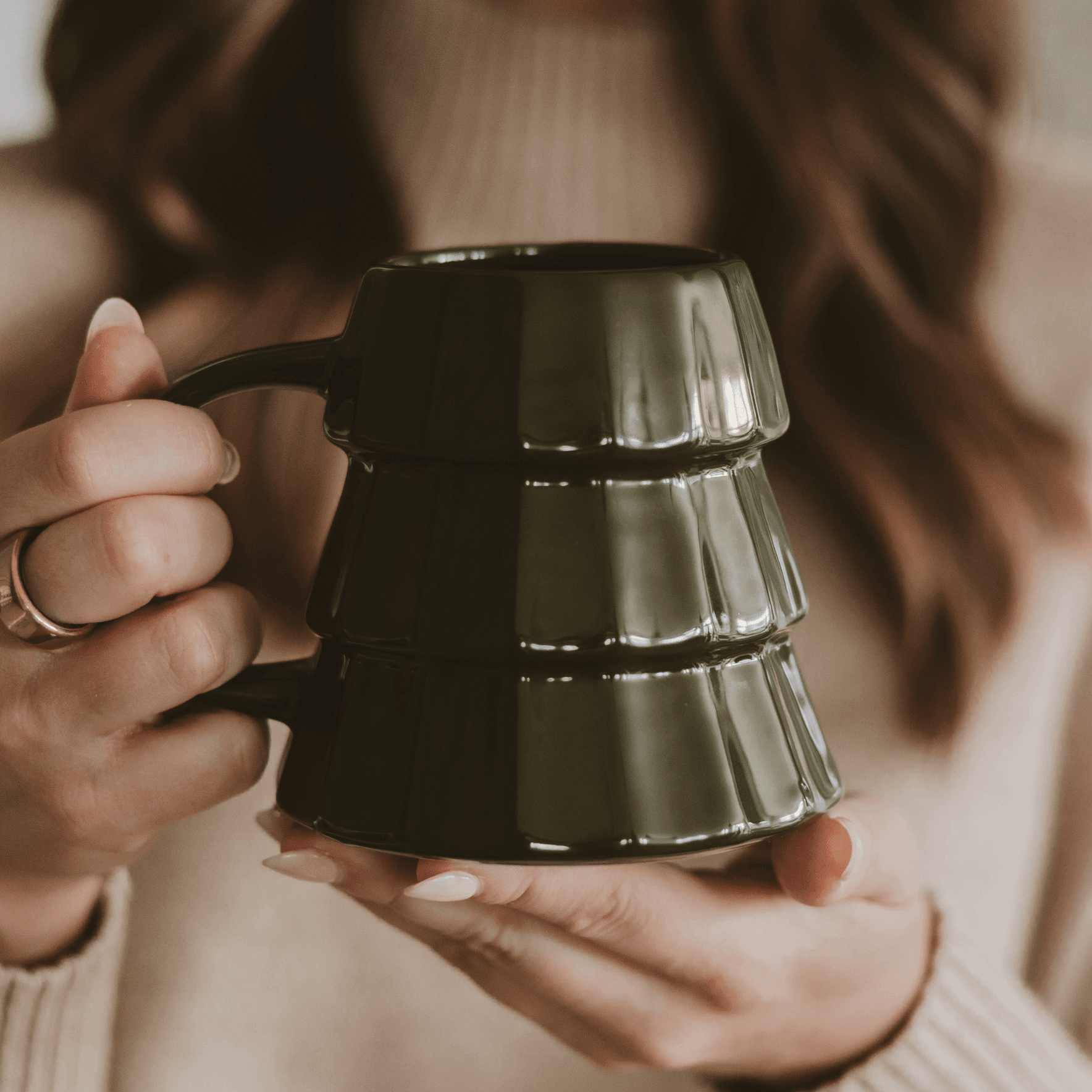 Person holding a black ceramic mug with a textured surface