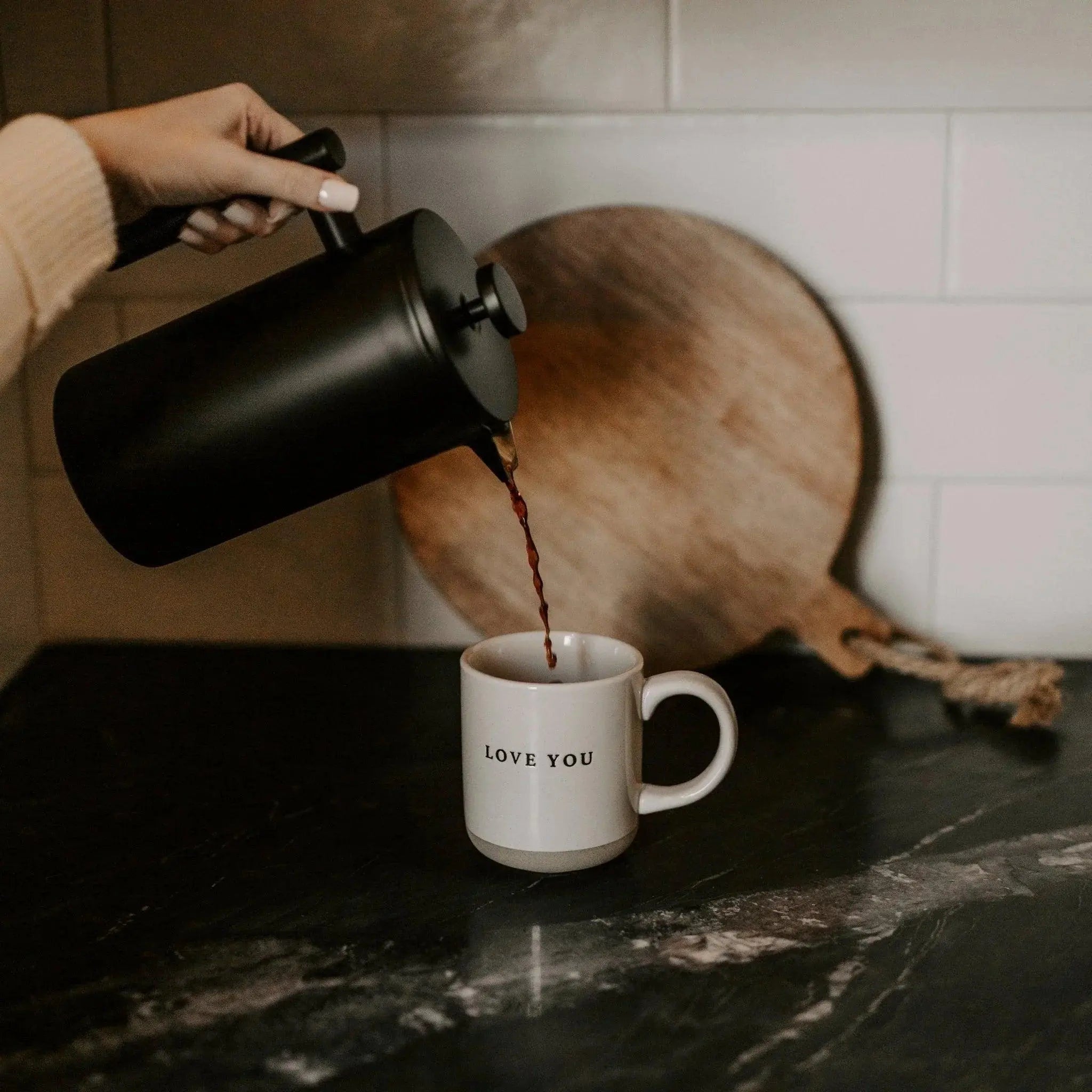 Pouring coffee into 'Love You' mug on dark countertop, cozy farmhouse kitchen decor