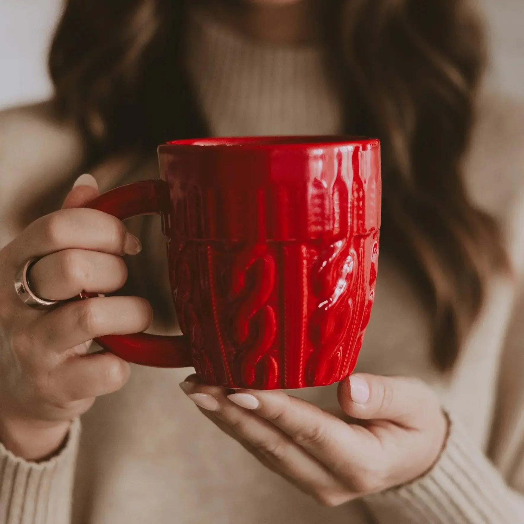 Red cable knit mug held by woman in cozy sweater, farmhouse home decor