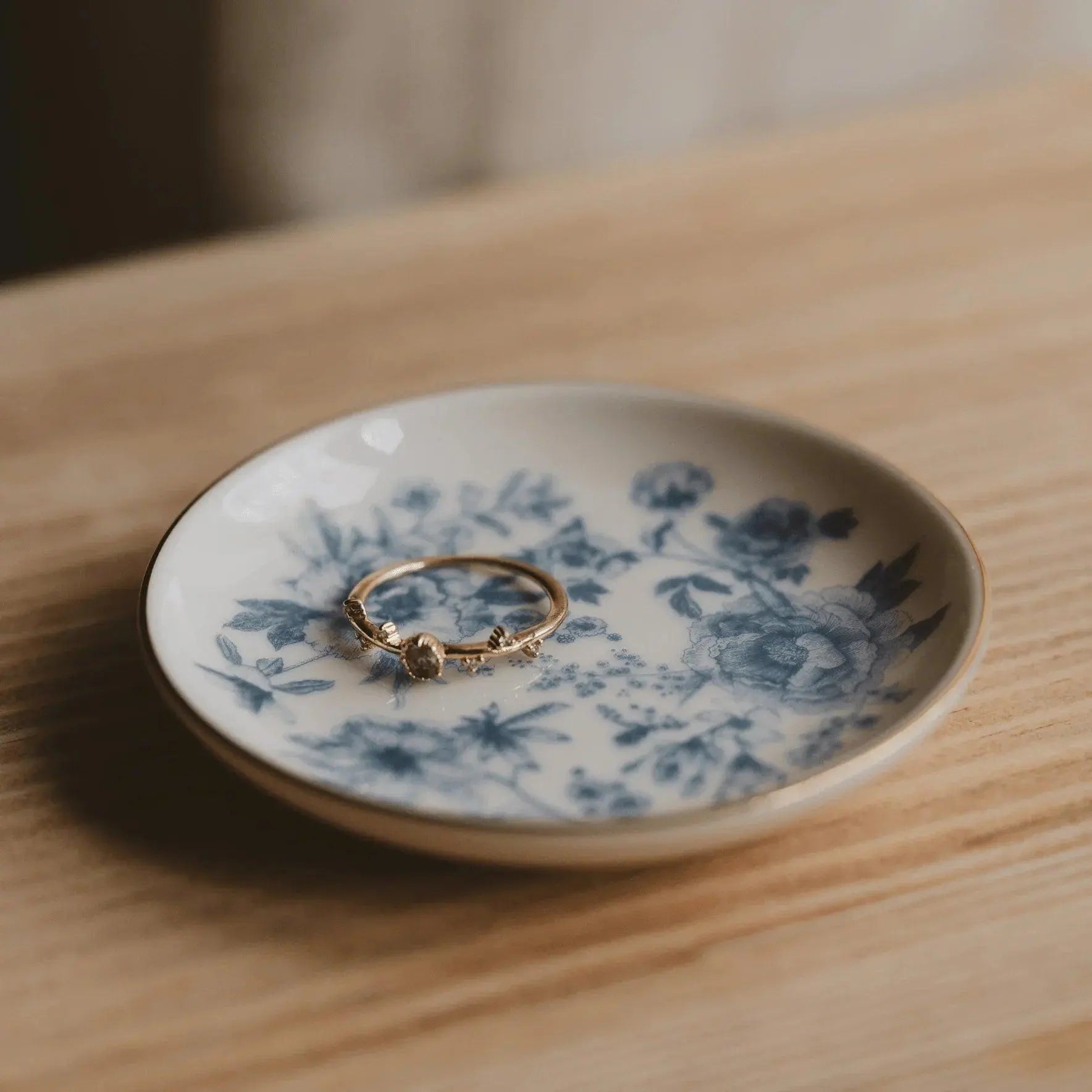 Gold ring on blue floral ceramic dish, cozy farmhouse decor for bedside or vanity