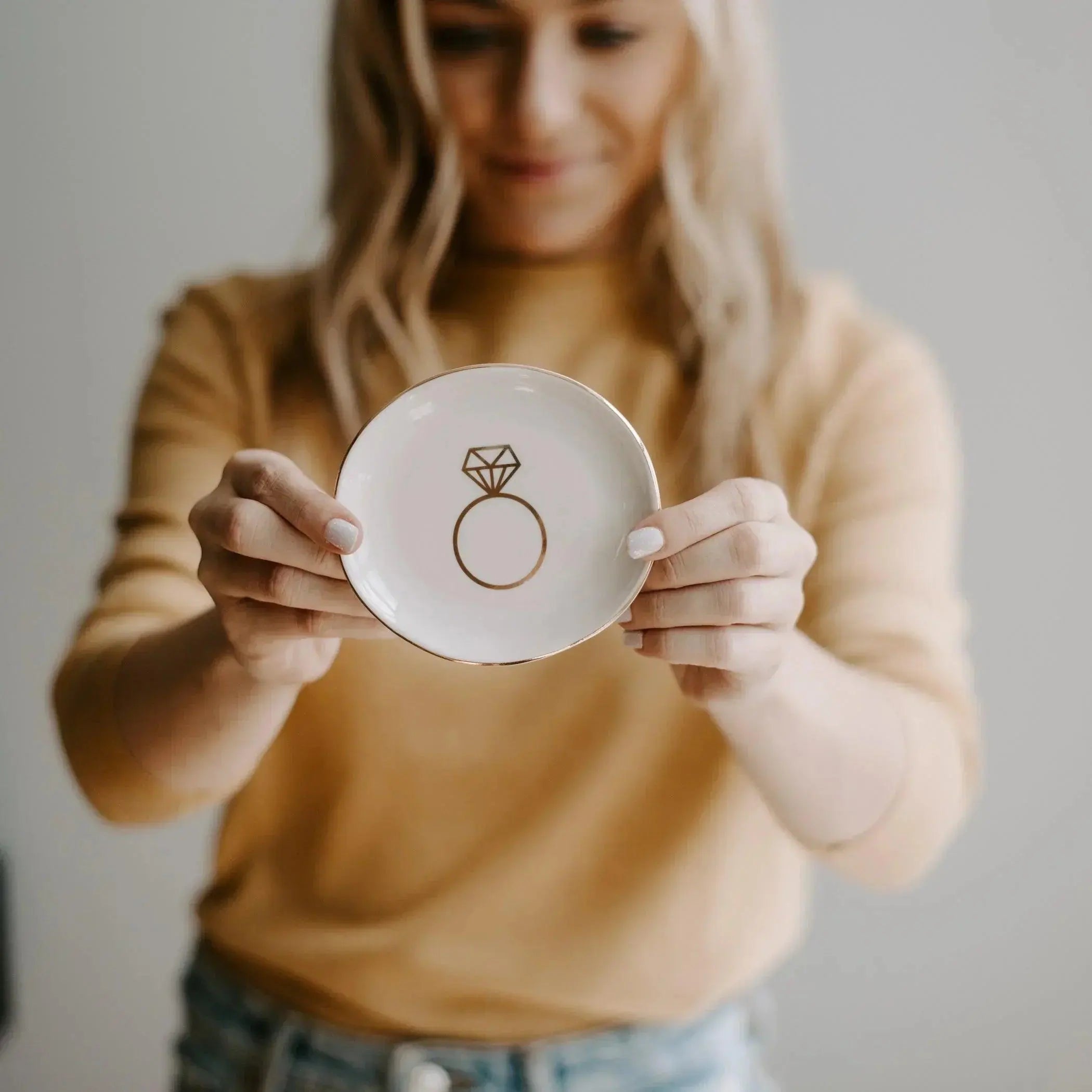Woman holding white ceramic ring dish with gold engagement ring design, cozy home decor accent