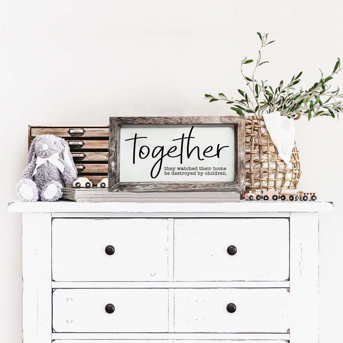 White dresser with decorative items including a framed sign, rabbit plush toy, and plant.