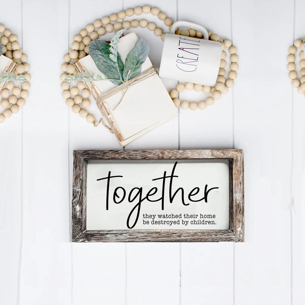Decorative setup with a framed sign, mug, and books on a white wooden surface.