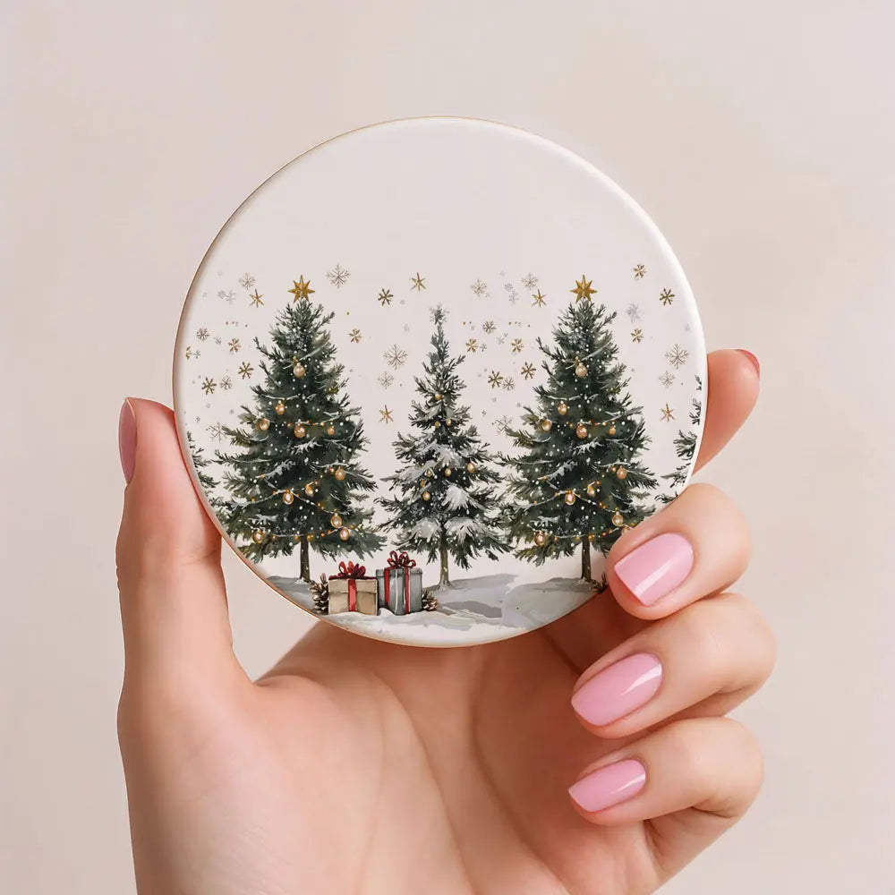 Round coaster with Christmas tree design held by a hand with pink nails on a beige background