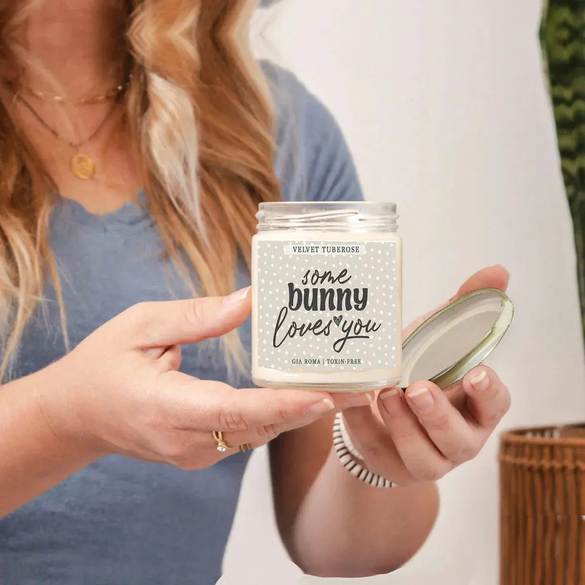 Person holding a candle jar labeled 'some bunny loves you' with a blurred background