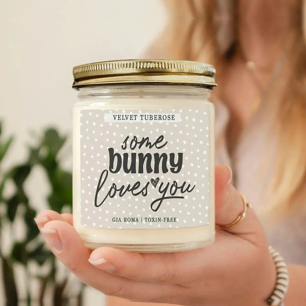 Candle jar labeled 'Some Bunny Loves You' held by a person with a blurred background