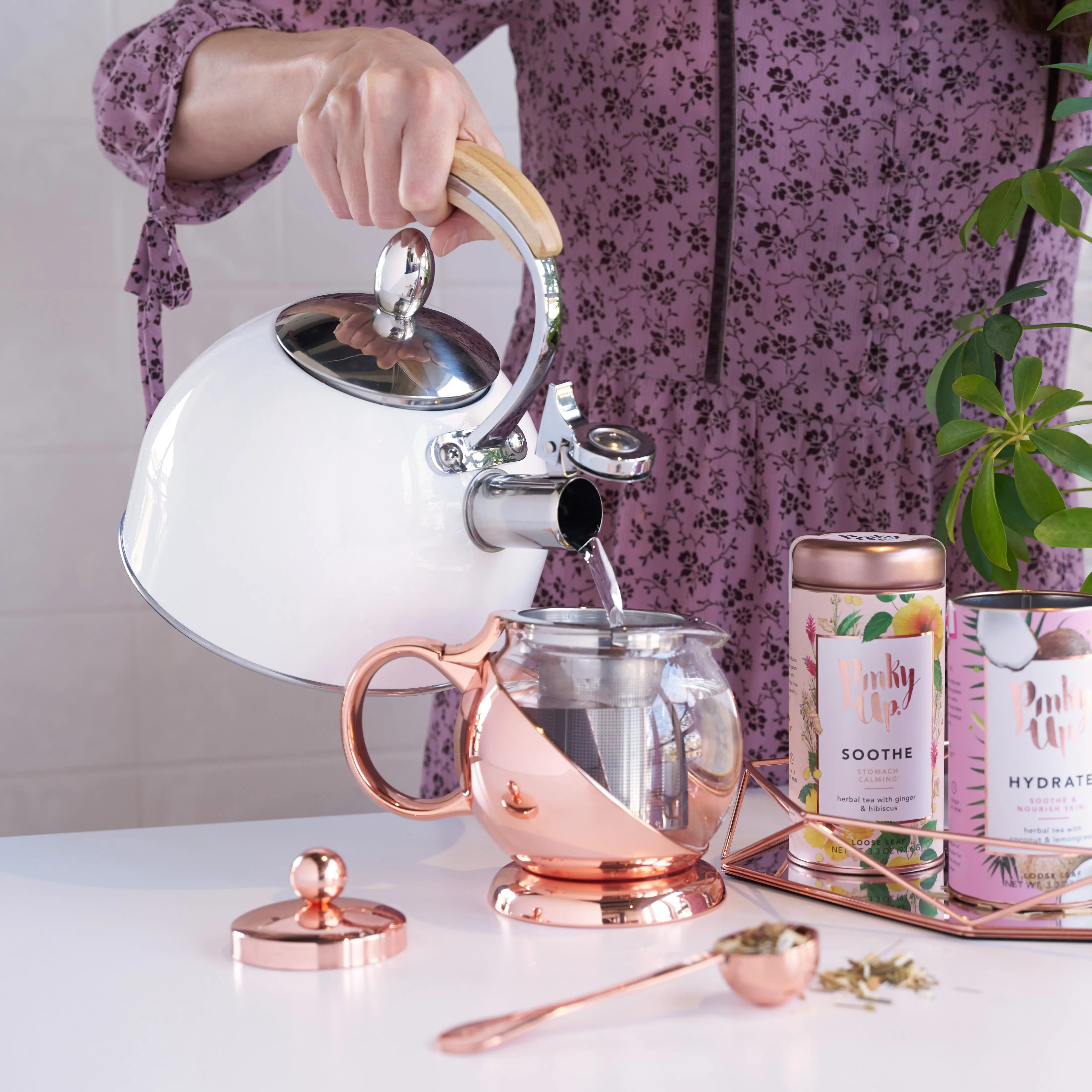Woman pouring tea from the Tea Pot with tea products surrounding