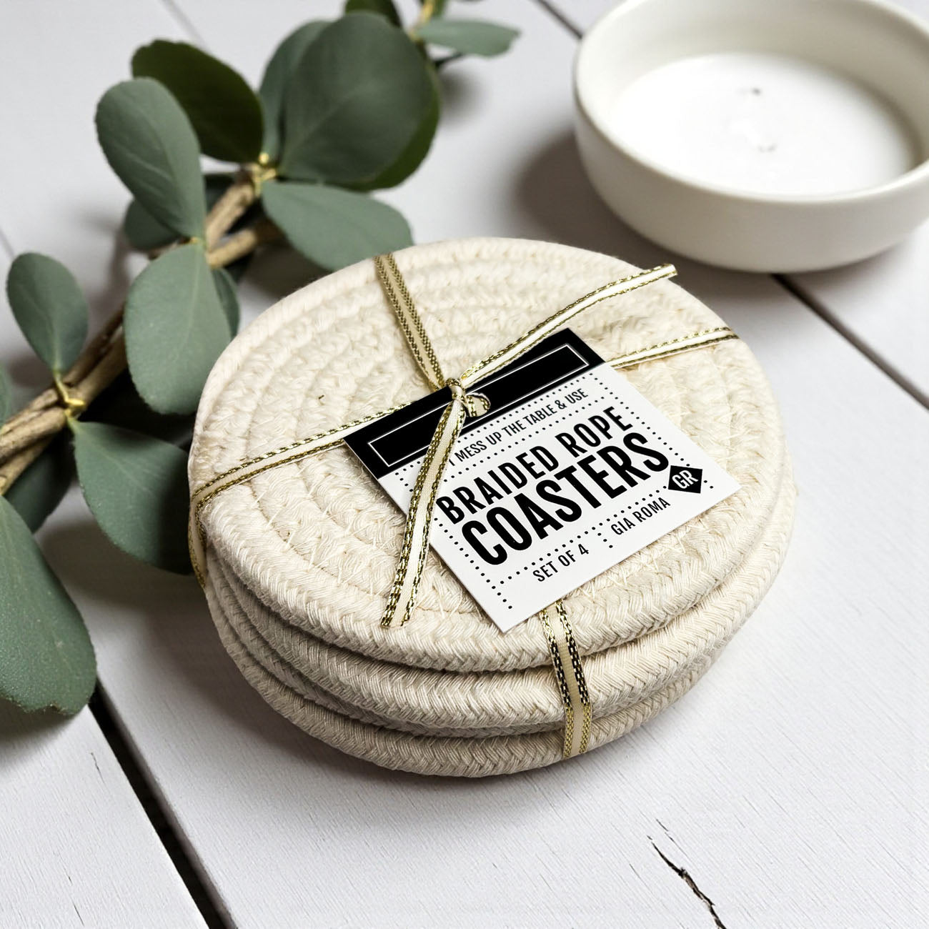 Set of braided rope coasters with a label on a white surface with greenery.
