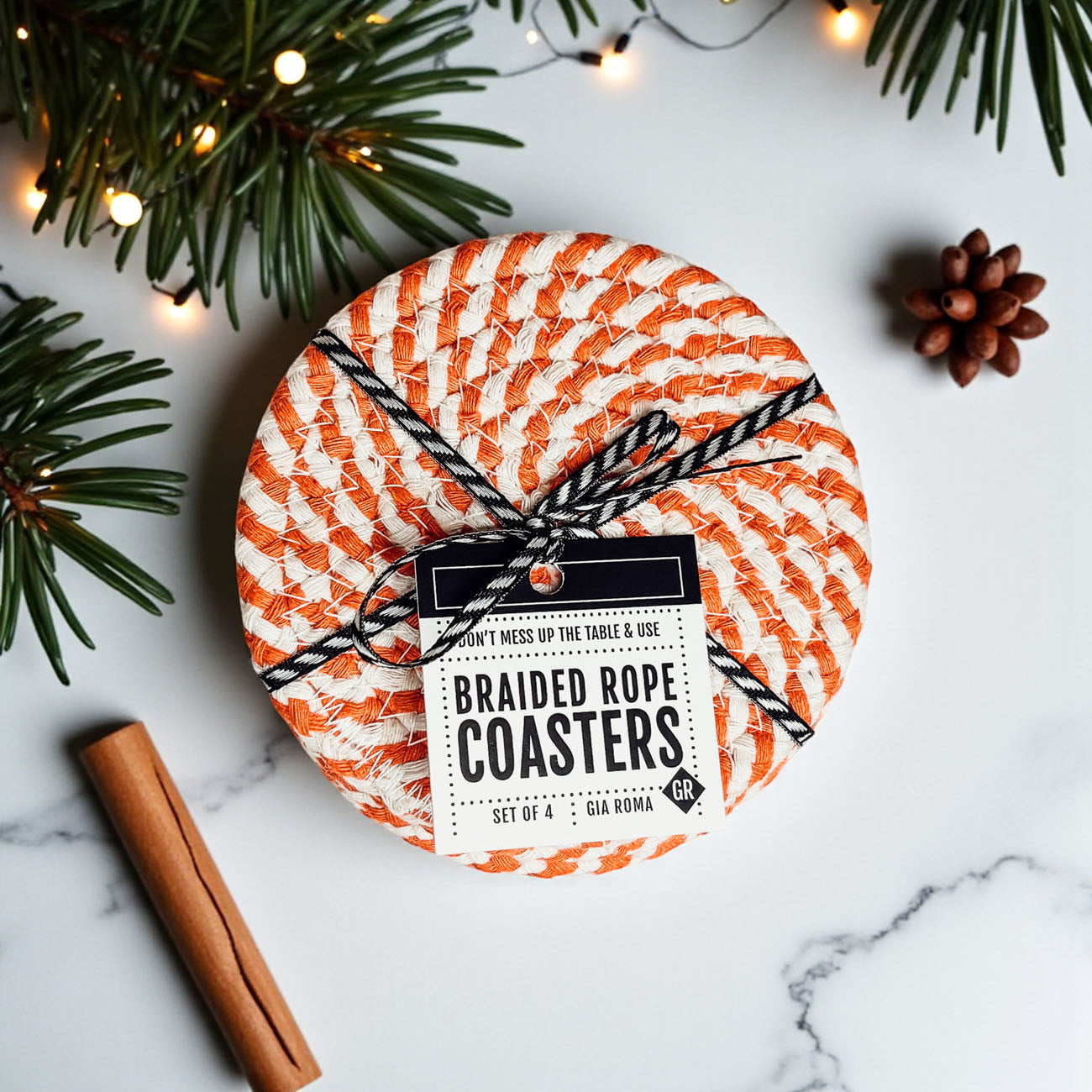 Pack of braided rope coasters with a label on a marble surface with Christmas decorations.